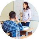Lehrsituation, Lehrende steht vor Whiteboard und erklärt Studierenden etwas. Lehrsituation, Lehrende steht vor Whiteboard und erklärt Studierenden etwas.